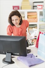 Woman using computer in clothes store.