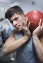 Young man at gym holding medicine ball.