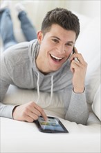 Young man using tablet and talking by phone.
