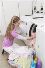 Woman loading laundry into washing machine.