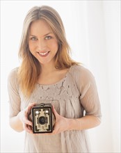 Portrait of young woman holding vintage camera.