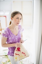 Female artist looking at painting in studio.
