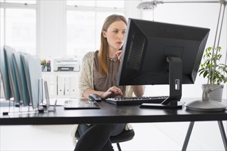 Portrait of young woman working on computer in office.