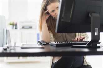Portrait of young woman working on computer in office.