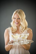 Portrait of young woman holding tray with champagne.
Photo : Jamie Grill