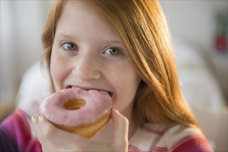 Portrait of girl (12-13) eating doughnut.
Photo : Jamie Grill