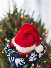 Rear view of kid (6-7) wearing santa hat.
Photo : Daniel Grill