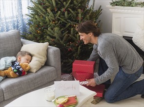 Man giving presents under Christmas tree while his son (6-7) sleeping.
Photo : Daniel Grill