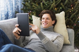 Man lying on sofa and using tablet.
Photo : Daniel Grill
