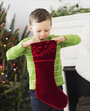 Boy (6-7) looking inside Christmas stocking.
Photo : Daniel Grill