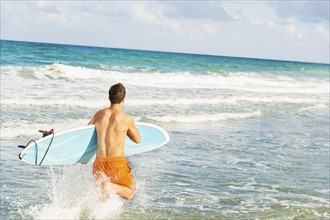 Young man carrying surfboard. Jupiter, Florida, USA.
Photo : Daniel Grill