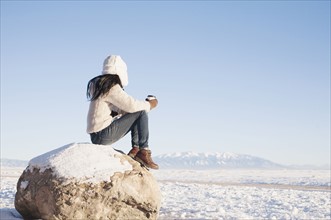 Woman sitting on rock with cup in winter. Colorado, USA.
Photo : Maisie Paterson