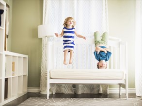 Girl (4-5) and boy (8-9) jumping on sofa.
Photo : Jessica Peterson