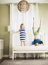 Girl (4-5) and boy (8-9) jumping on sofa.
Photo : Jessica Peterson