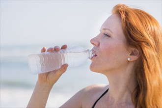 View of woman drinking water on beach.