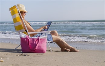 Woman sitting on deckchair and using laptop.