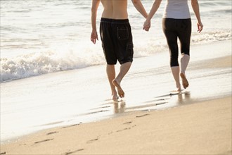 Couple walking on beach, low section.