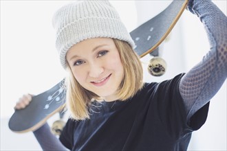 Portrait of young woman holding skateboard.