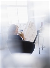 Business woman looking at blueprint in office.