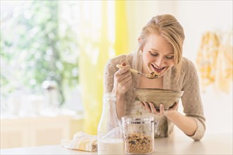 Young woman eating granola for breakfast.