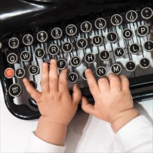 Studio shot of babies(6-11 months) hand touching typewriter.