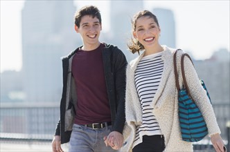 Young couple walking, buildings in background.