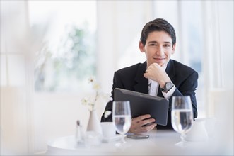 Portrait of business man using digital tablet in restaurant.
