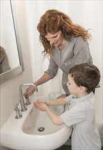 son (6-7) and mother washing hands.