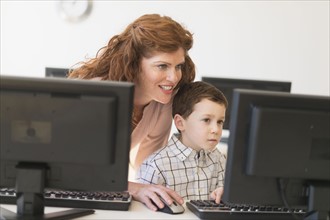 boy (6-7) and teacher using computer.