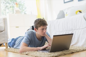 Teenage boy (16-17) using laptop.