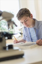 Teenage boy (16-17) reading book in laboratory.