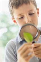 boy (8-9) looking through magnifying glass.