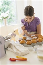 girl (10-11) decorating cakes.