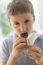 boy (8-9) eating ice cream sandwich.