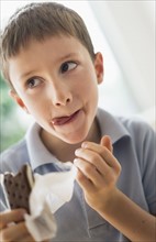 boy (8-9) eating ice cream sandwich.
