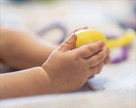 Hands of baby girl (6-11 months) holding toy.
