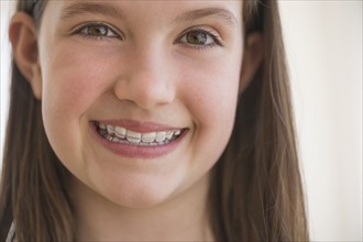 girl (10-11) wearing dental braces smiling.