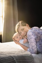 Portrait of smiling Mother holding baby boy (2-5 months) in bedroom.