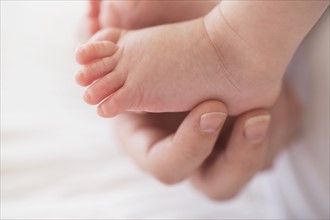 Close up of mother's hand touching baby boy's(2-5 months) foot.