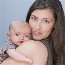 Portrait of smiling mother holding baby boy (2-5 months) on her arm.