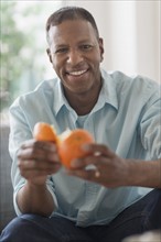 Portrait of smiling man peeling orange fruit.