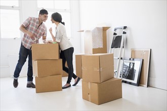 Young couple standing among boxes in new home.