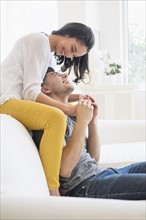 Happy young couple playing on sofa.