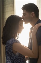 Young couple kissing in sunlight.
