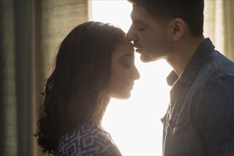 Young couple kissing in sunlight.