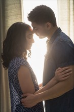 Young couple embracing in sunlight.