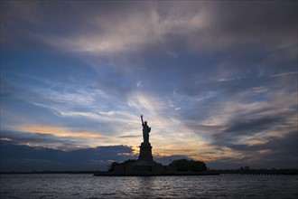 Silhouette of Statue of Liberty at sunset.