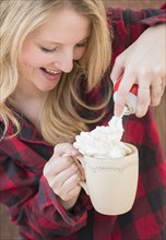 Portrait of woman spraying whipped cream into hot chocolate.
Photo : Jamie Grill