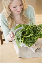 Woman holding colader full with kale.
Photo : Jamie Grill