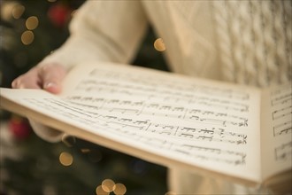 Studio Shot of woman holding sheet music at christmas.
Photo : Jamie Grill